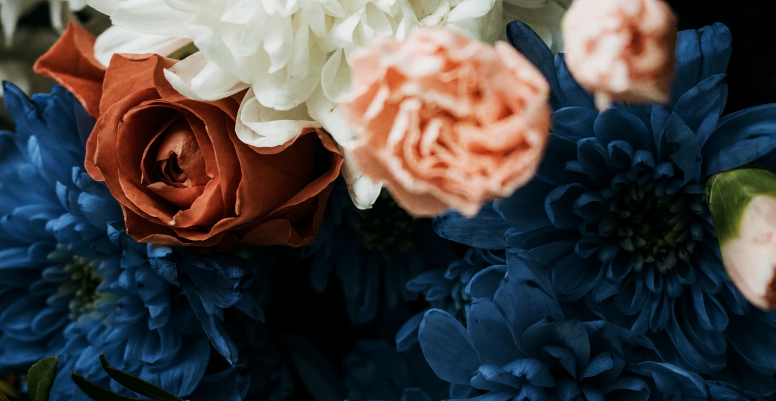 Detalle de flores azules, blancas y terracota en un arreglo natural