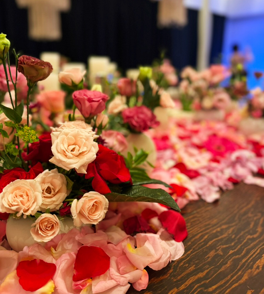 Montaje floral romántico con rosas y pétalos sobre mesa de evento