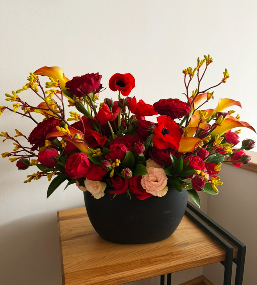 Arreglo floral en tonos rojos y naranjas en base negra