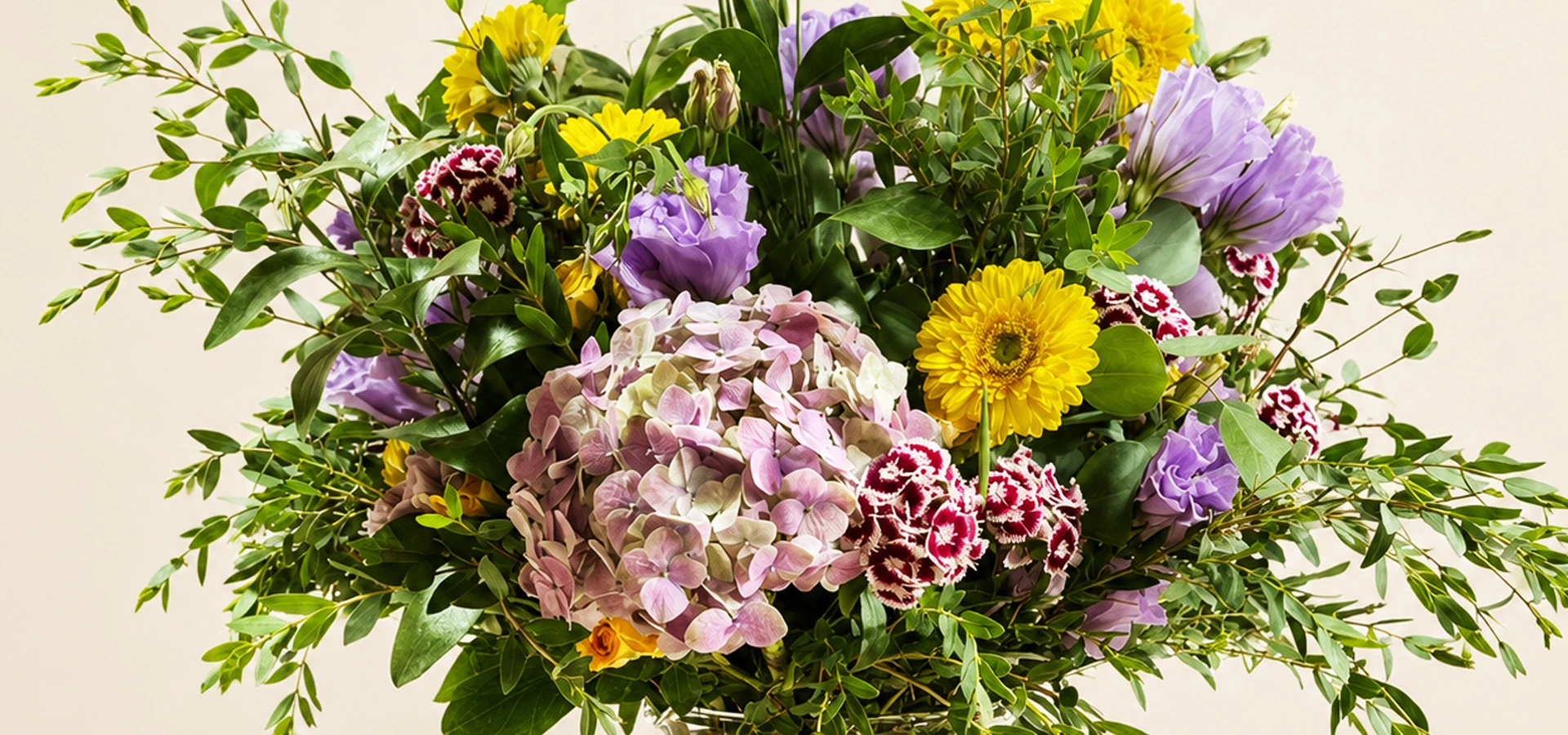 Arreglo floral con hortensias rosas, gerberas amarillas y follaje verde