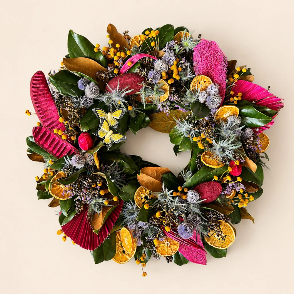 Corona floral artesanal con flores, follajes y elementos naturales