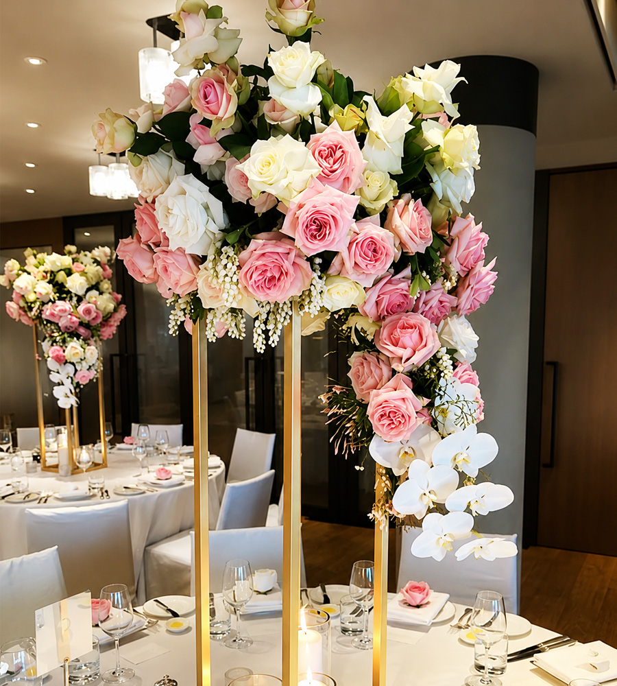 Arreglo floral alto con rosas, orquídeas y estructura dorada para evento