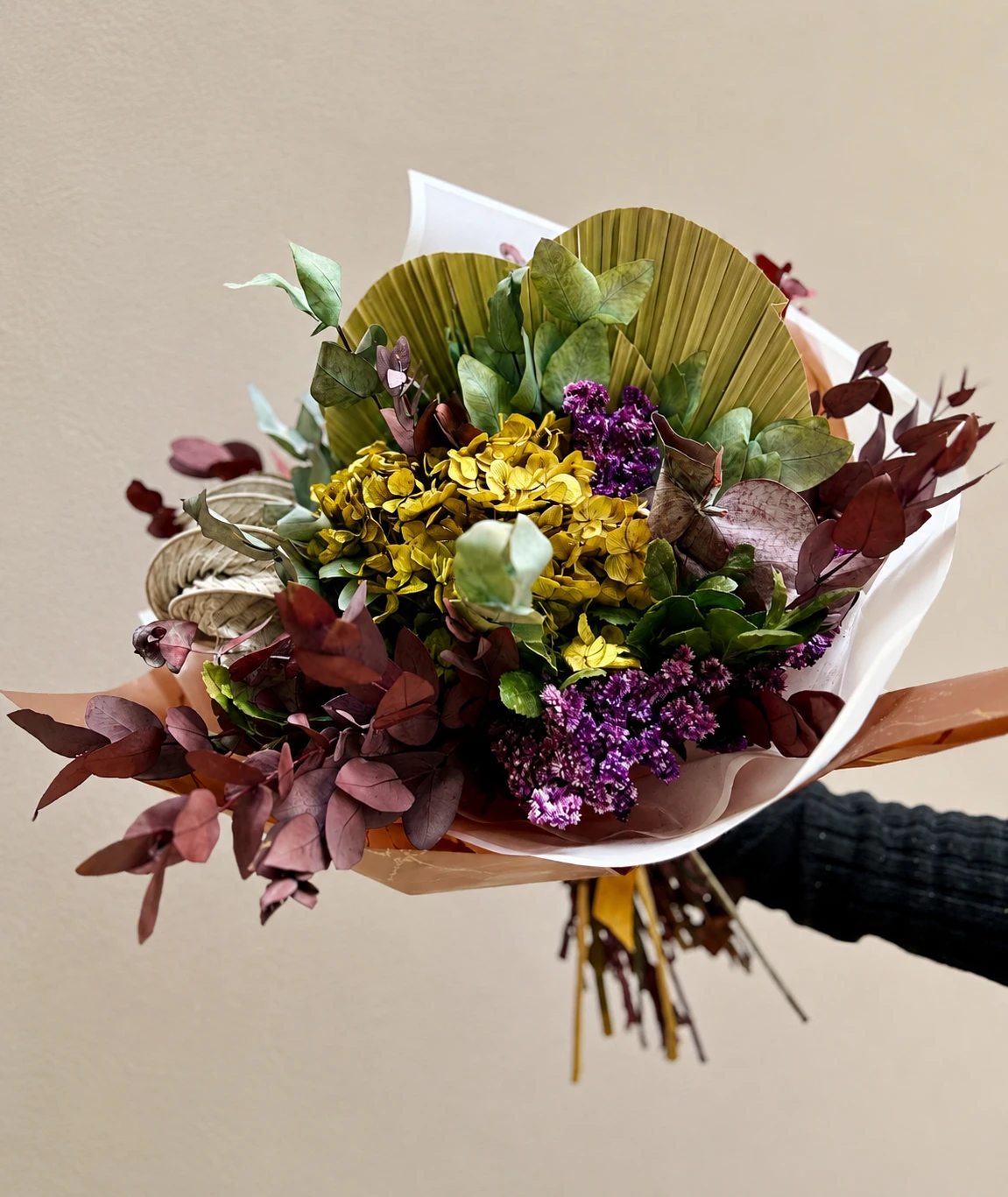 Pieza floral vertical con hoja de palma y follaje rojo profundo